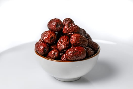 Dried Chinese dates in a ceramic cup on a white background