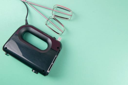 Kitchen electric hand mixer for mixing whip or eggs isolated on mint background. Top views with clear space
