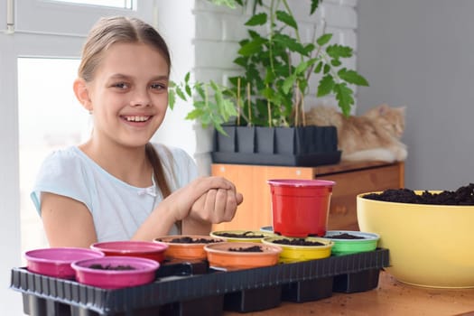 The girl clutched the seeds in her hands for planting and looks into the frame with a smile