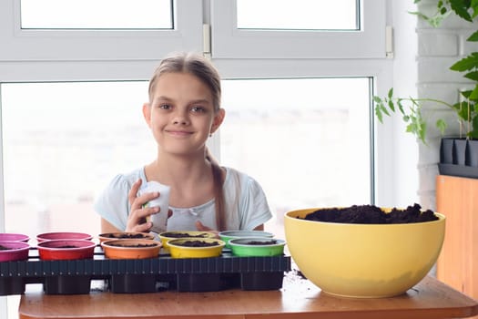 Girl with bags of seeds and pots of earth sitting at the table