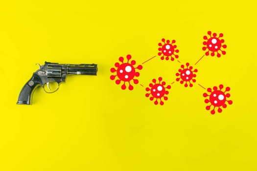 A black gun and a drawn COVID-19 virus. The coronavirus epidemic kills people and causes death. COVID-19 infection concept.