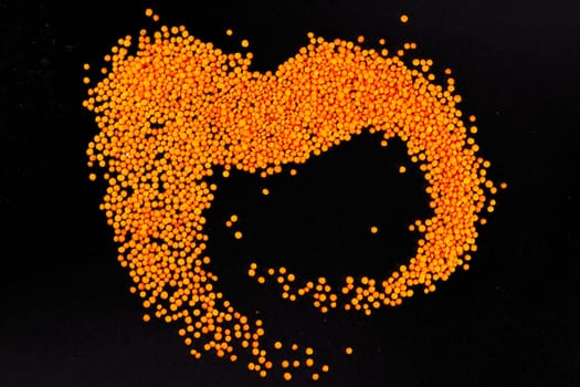 Red lentils on a black background. Top views.