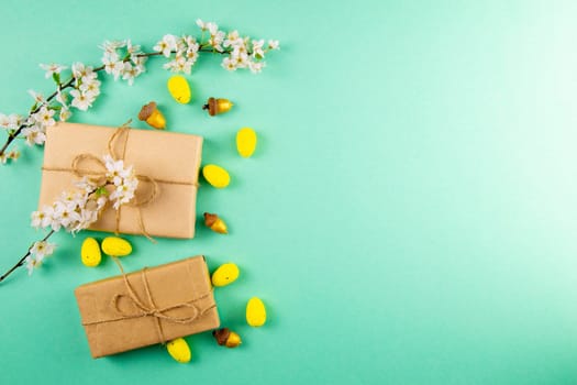 Two easter gifts, yellow eggs and white spring flowers on a mint background close-up. Easter background.