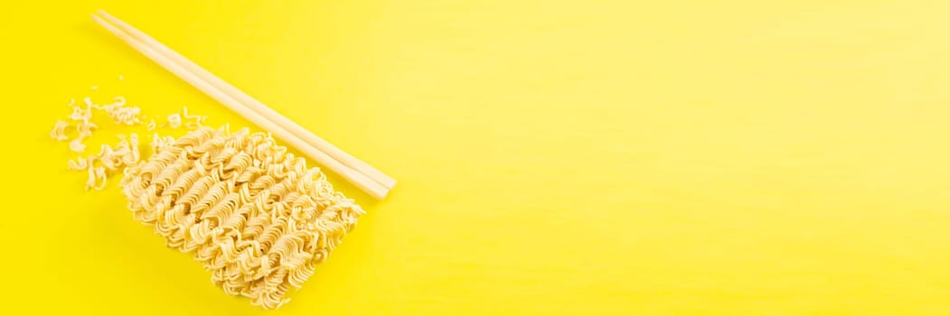 Instant noodles with wood sticks. Asian fast food on a yellow background close-up. Top views.