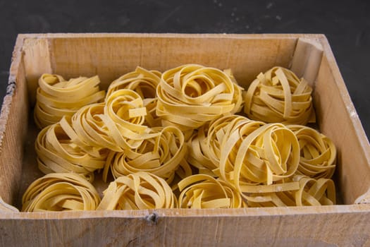 Raw tagliatelle in a wooden box. Front views