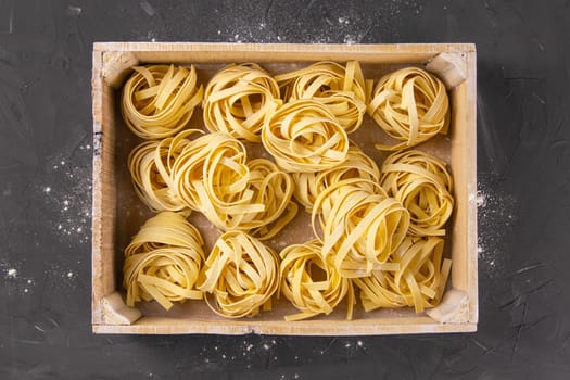 Raw tagliatelle in a wooden box. Top views
