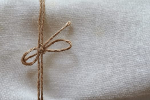Twine tied in a bow. Close-up. Fabric background