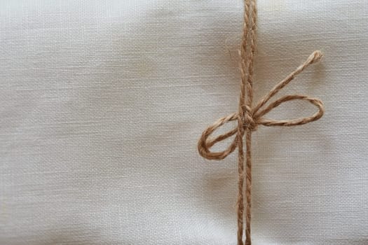 Twine tied in a bow. Close-up. Fabric background