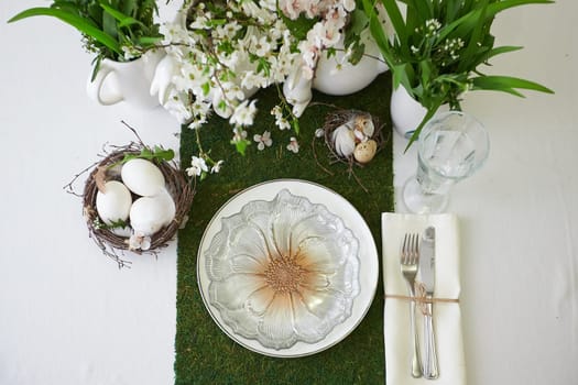 Easter table set. Decorated with eggs, nests and flowers.