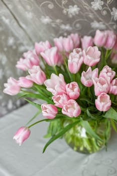 Decor and a vase with pink tulips on a table. Selective focus.