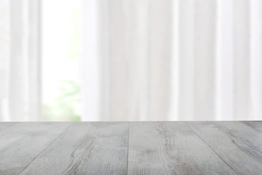 Empty rustic wooden bright table top in front of blurred curtain window natural green background. Template for your product display montage. Space for design.