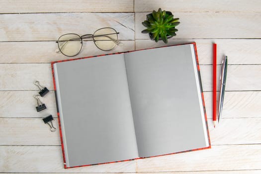 Open notebook, pen, glasses and green flower on a gray wooden background, texture. Office and holiday concept, place for the inscription. top view with clear space