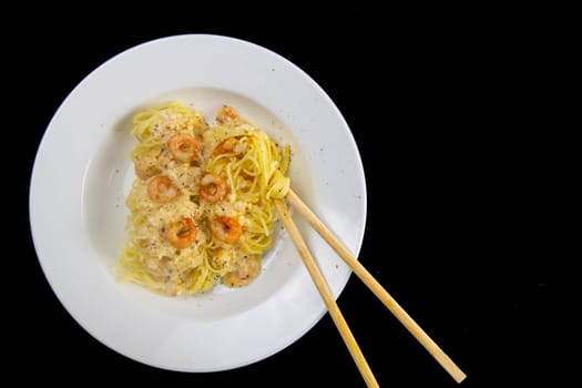 Spaghetti shrimp in white dish, top view noodles spicy with seafood isolated on black background - Clipping Path, Top views.