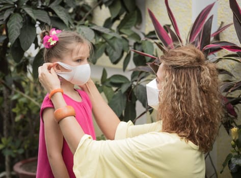 Woman and daughter wearing facial disposable mask to avoid viral infection. Coronavirus protection