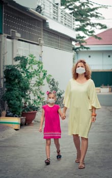 Woman and daughter wearing facial disposable mask to avoid viral infection. Coronavirus protection