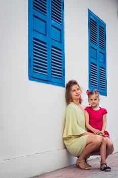 Mother and daughter next to shutter window in a street