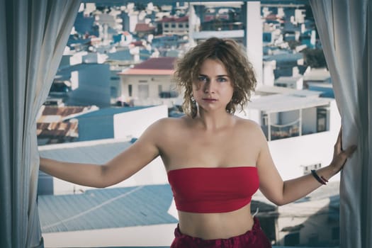 Fashion style portrait of a beautiful woman in red on a balcony