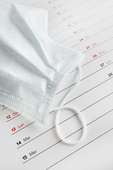 Montly calendar with self protection face mask. Coronavirus concept. Beginning / end of the pandemic. Deadline concept with sheet of monthly calendar. Coronavirus COVID-19. Copy space. Selective focus.