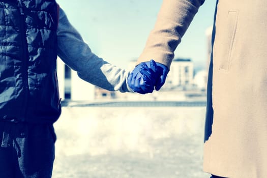 Man and child holding hands wearing medical gloves for protection from Coronavirus Covid - 19