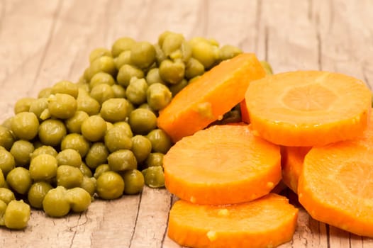 Peas and carrot rings close-up on a wooden background