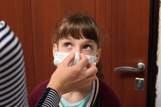Mom corrects a protective medical mask on the face of a child