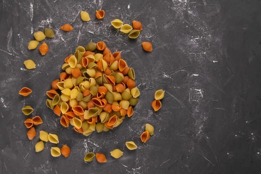 Pasta Conchiglie Rigate, mix of colorful uncooked shells In the form of a circle. Textured Italian food background concept. Top view flat lay close up, clear space.