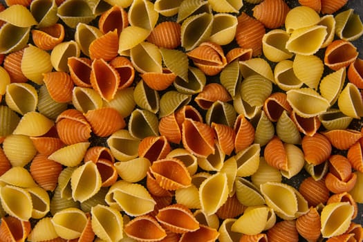 Conchiglie paste of different colors isolated on black background.