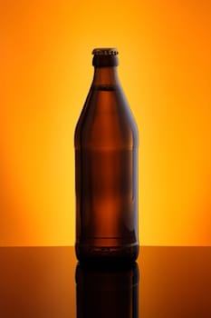 Brown beer bottle with crown cork in orange back lit