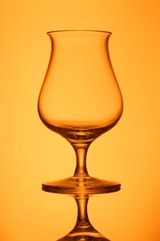 Lucid empty whisky glass in orange back lit vertical format