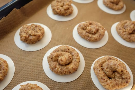 Raw hazelnut macaroons on griddle and baking paper