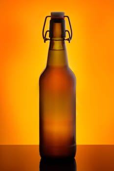 Brown beer bootle with swing top in orange back lit