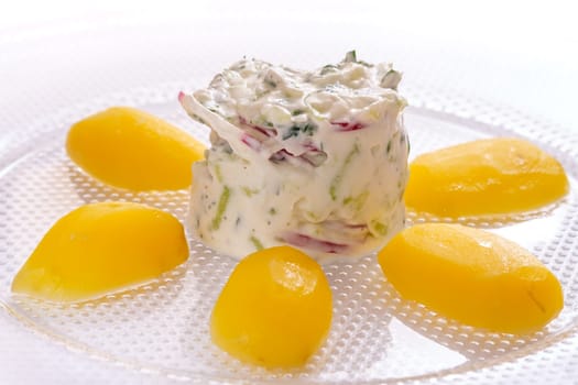 Potatoes with curd cucumber and radish on a glass plate