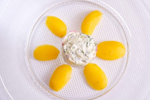 Top view glass plate with potatoes cucumber radish and curd