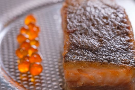 Fried salmon fish with skin and caviar as close-up