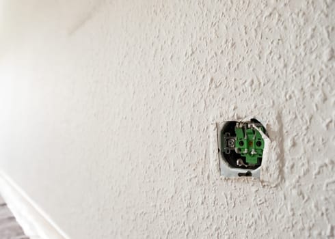 Open socket at a wall with woodchip wallpaper in back lit