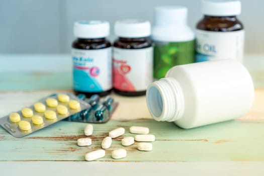 Variety of medicine spilling and pill bottle on vintage wooden background. Using as health care and medical cure and pharmaceutical industry background.