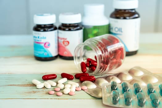 Variety of medicine spilling and pill bottle on vintage wooden background. Using as health care and medical cure and pharmaceutical industry background.