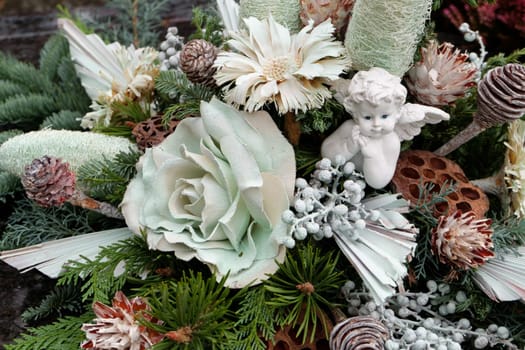 Floral arrangement with angel und rose flower and pine twigs