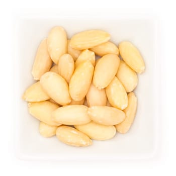Peeled almonds in a white square bowl in top view