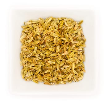 Fennel seeds in a white square bowl in top view
