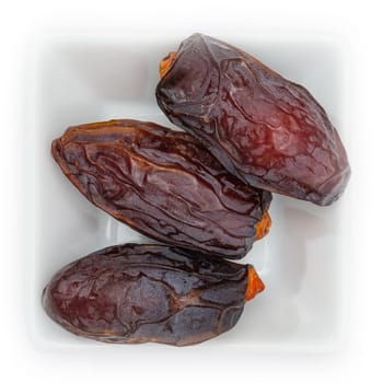Dried date fruit in a white square bowl in top view