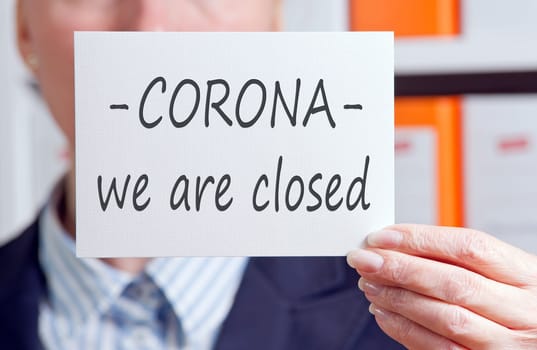 Businesswoman with sign, Corona, we are closed