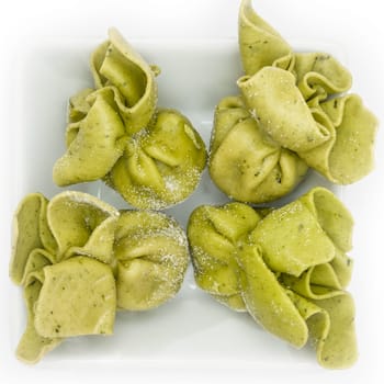 Green tortellini pasta with cheese and spinach filling in white bowl