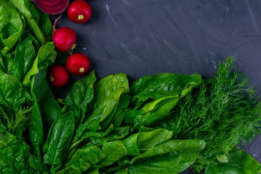 Fresh vegetables and greens radish, spinach, beet on a black background. Top views, clear space