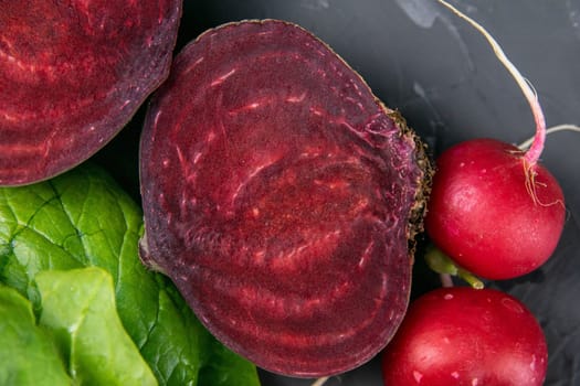 Fresh vegetables and greens radish, spinach, beet on a black background. Top views, clouse-up