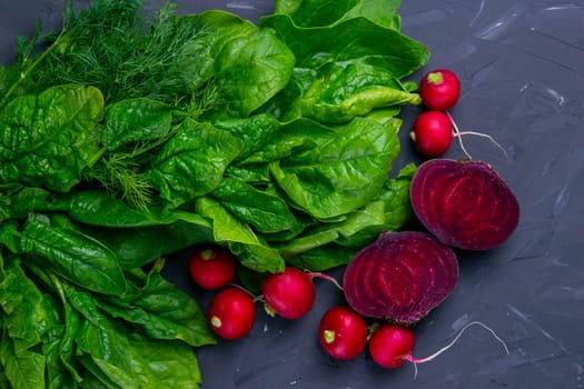 Fresh vegetables and greens radish, spinach, beet on a black background. Top views, clouse-up