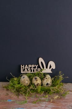 Quail eggs stand in a nest of green moss next is a sign of the Happy Easter. Top views with clear space