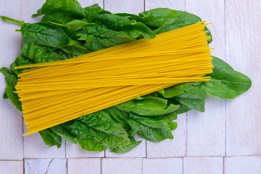 Creative layout made of spinach and noodles on white wooden background. Flat lay. Food concept. Macro concept.