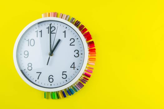 A set of cosmetic tools for manicure and pedicure on a blue background. The watch and palette of colors for manicureons on tips stands under the clock all standing on a yellow background.