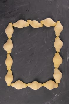 Conchiglie pasta shell composition in the shape of a rectangle with an empty middle on black background with clipping path. Concept of dough products and pastry.